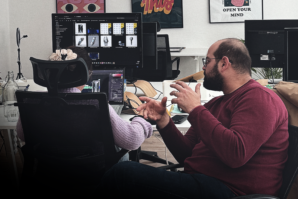 Dois profissionais da Slide Lab a conversar num espaço de trabalho com computadores.