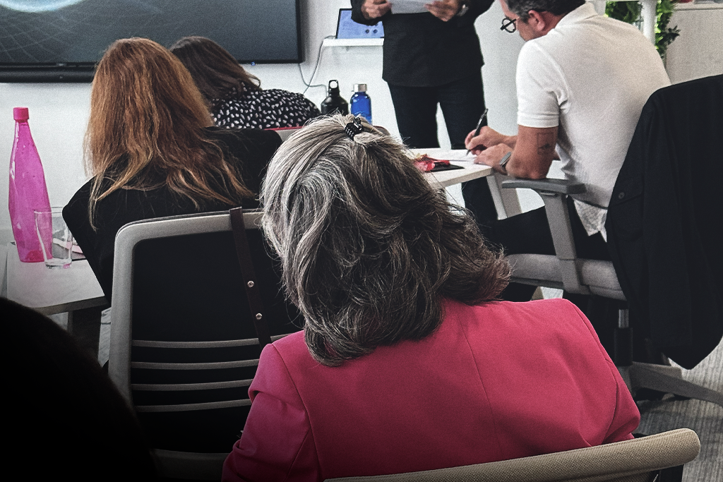 Participantes numa sessão de formação presencial, sentados em sala e a acompanhar o formador.